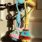 Two colorful dog toys hanging on a doorknob with a neutral background.