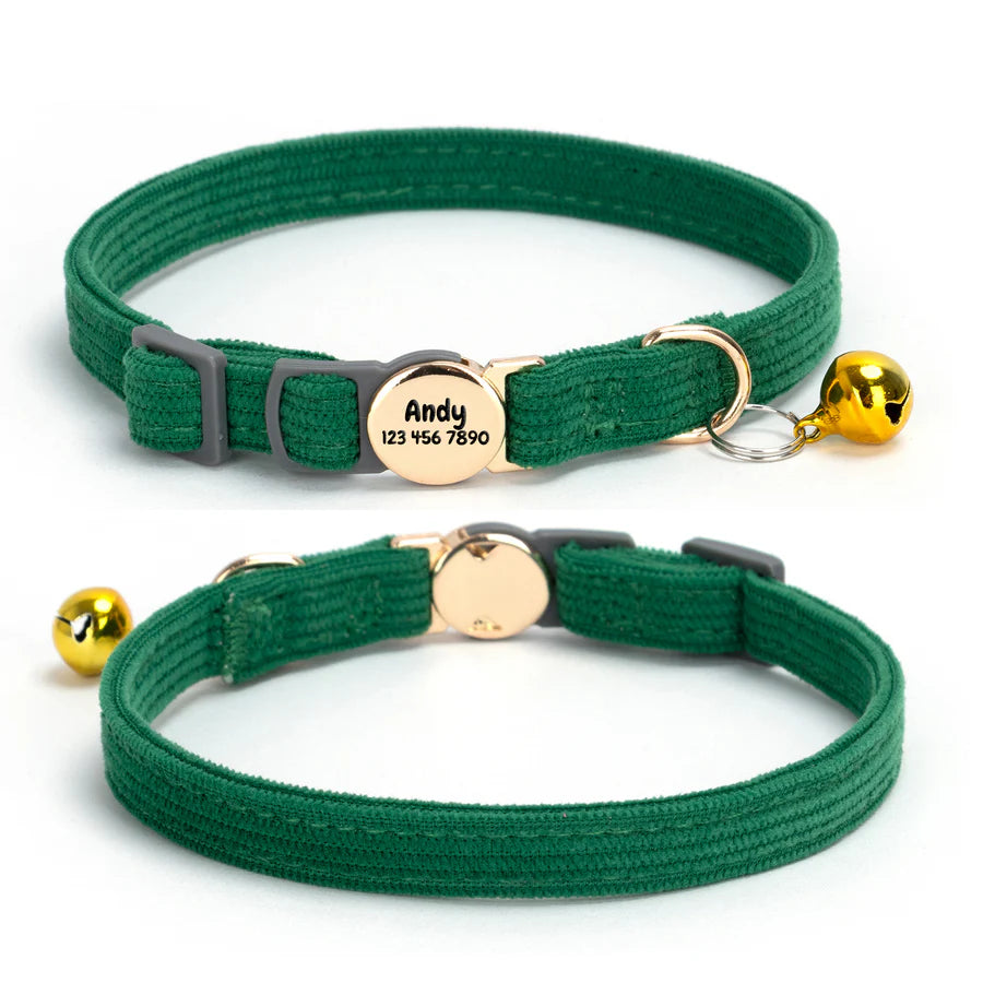 Two green cat collars with gold bells and engraved tags on a white background