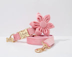 Pink flower-shaped dog collar and leash set with a gold tag on a light gray background